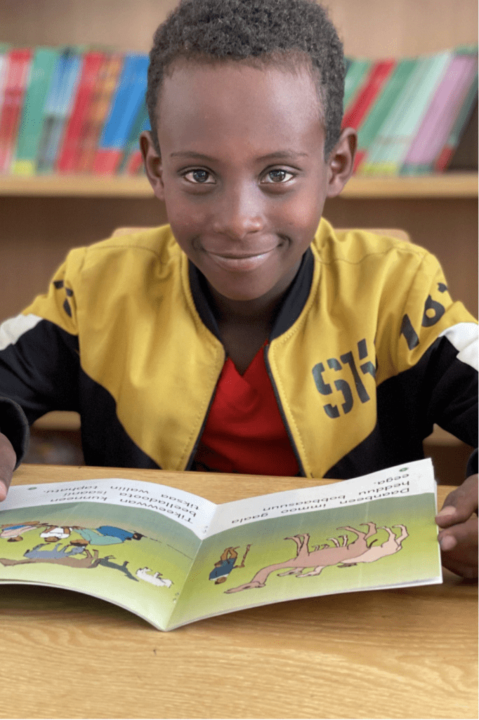 A second grade boy named Samuel reads a book at a desk